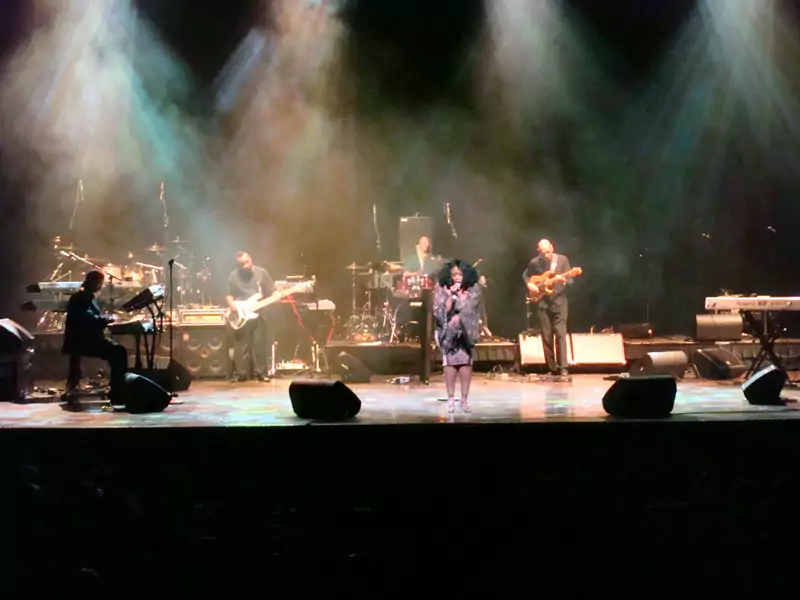Band performing on a lit stage with backline instruments