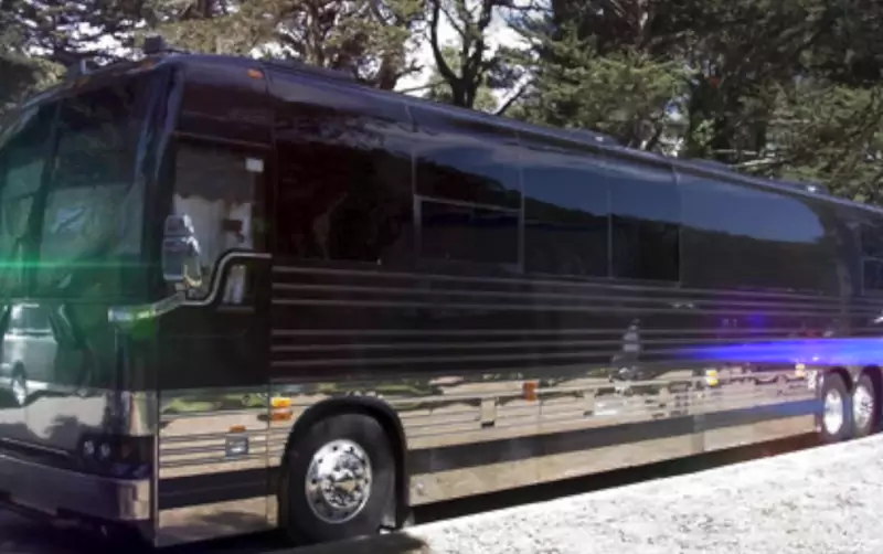 Black tour bus parked under trees