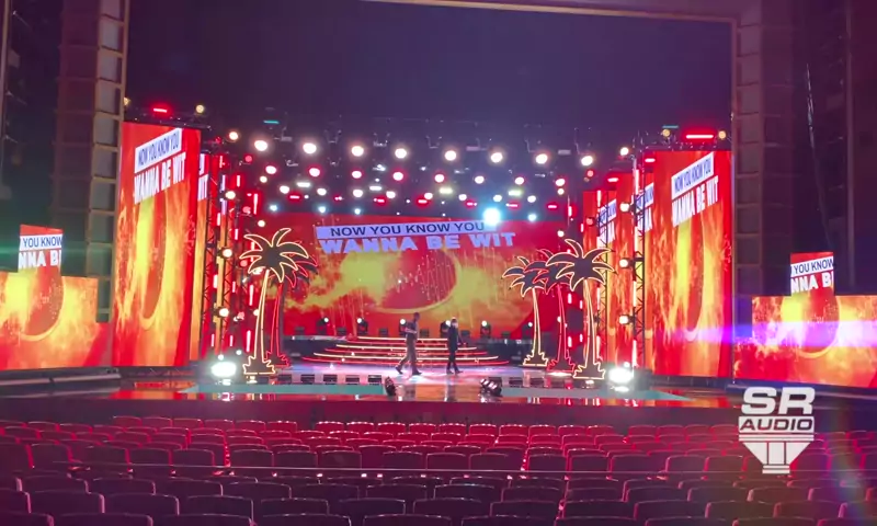 The finished stage in a theater: LED walls, palm trees and lighting, built from the rendering